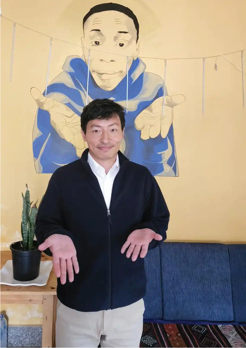 men with yellow wall behind and black jacket