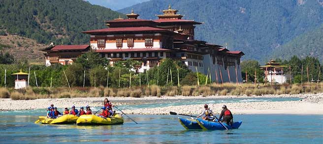 People doinf river raffting and dzong behind