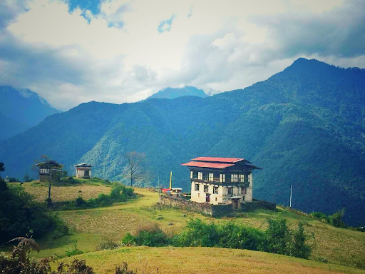 Bhutan traditional house behind green mountain and clouds