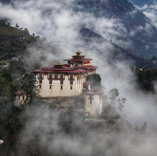 Luntshe dzong ontop of mountain and surrounded by clouds